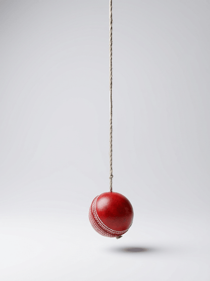 Suspended red leather cricket ball showing swinging motion for technique